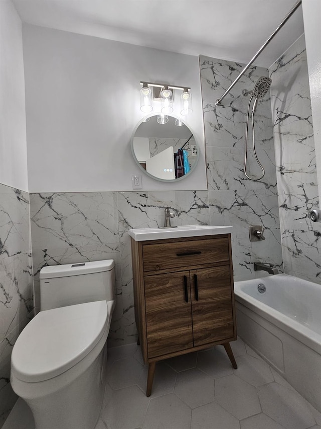 full bathroom featuring tiled shower / bath combo, toilet, tile walls, and vanity