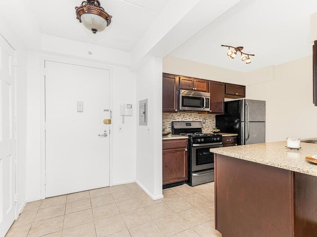 kitchen featuring light tile patterned floors, backsplash, stainless steel appliances, and light stone counters