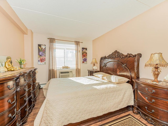 bedroom featuring hardwood / wood-style floors and a baseboard heating unit