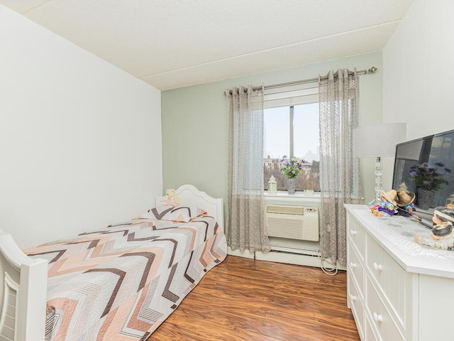 bedroom featuring hardwood / wood-style floors, a baseboard radiator, and a wall mounted AC