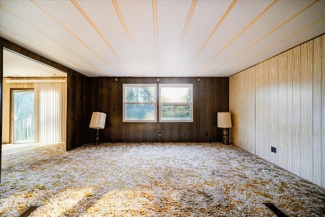 spare room with carpet flooring, wood walls, and a textured ceiling