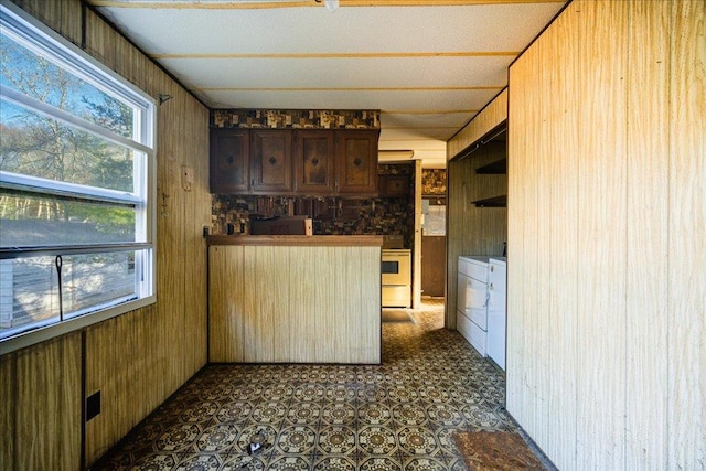 kitchen featuring washer and dryer, wood walls, and white range oven