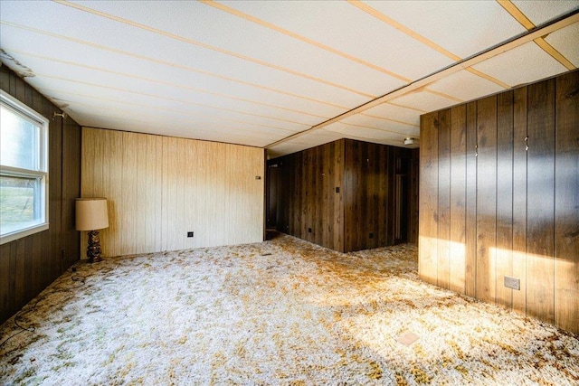 carpeted spare room featuring wood walls