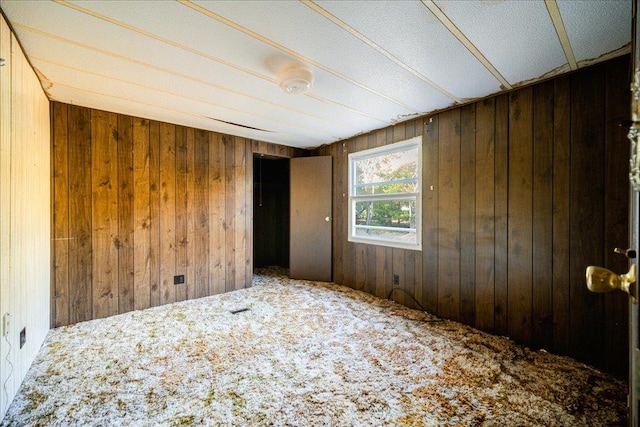 carpeted spare room with wooden walls