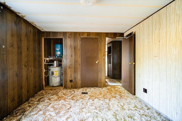 carpeted bedroom with wood walls and water heater