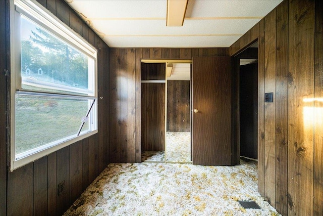 carpeted bedroom featuring wood walls and a closet