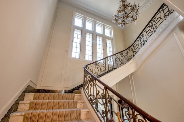 staircase featuring a towering ceiling and crown molding