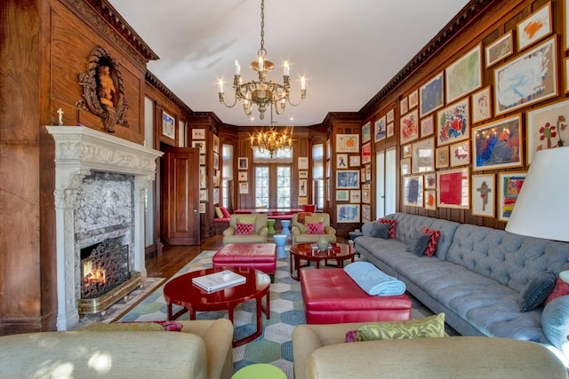 living area featuring french doors, an inviting chandelier, a fireplace, and crown molding