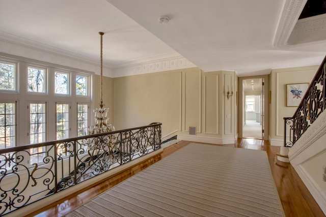 corridor with light hardwood / wood-style flooring, an inviting chandelier, and crown molding