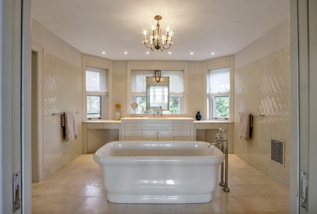 bathroom with a bath, an inviting chandelier, and vanity