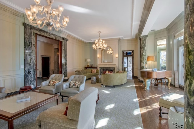 living room with carpet floors, a high end fireplace, ornamental molding, and a chandelier