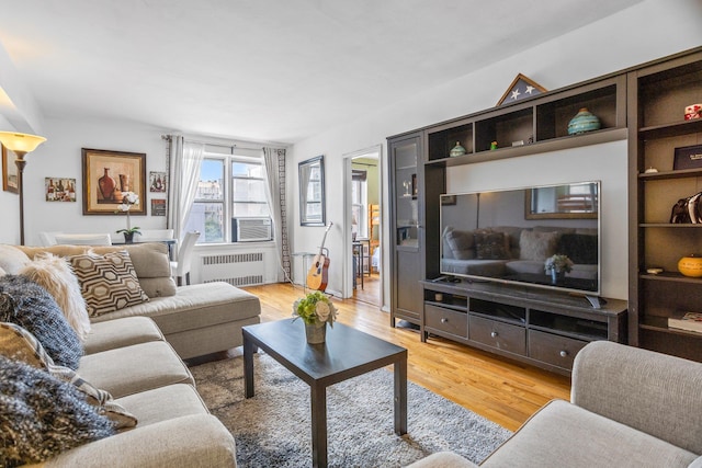 living room with radiator, cooling unit, and light hardwood / wood-style floors