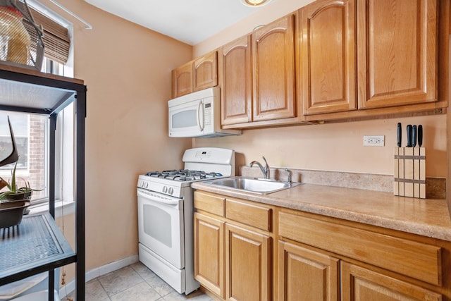 kitchen with light tile patterned flooring, white appliances, and sink