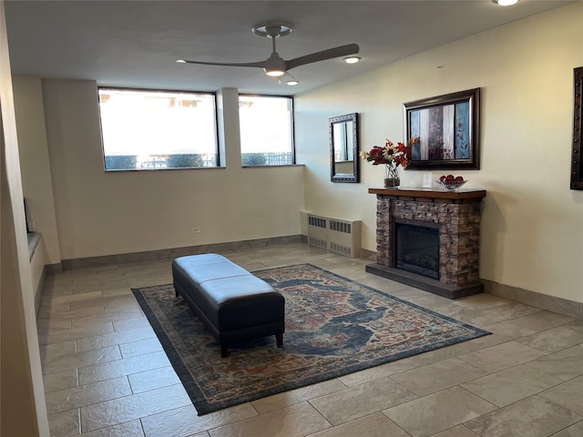 living area featuring a healthy amount of sunlight, a fireplace, radiator heating unit, and ceiling fan