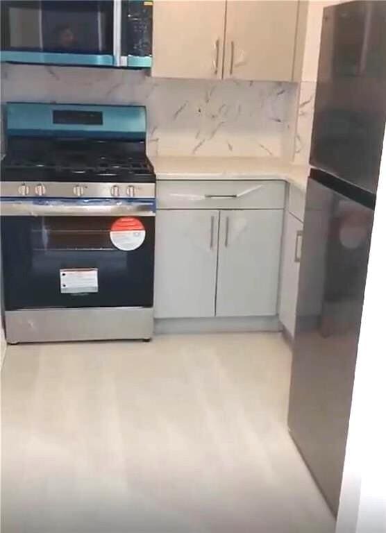 kitchen featuring appliances with stainless steel finishes, backsplash, and light stone counters