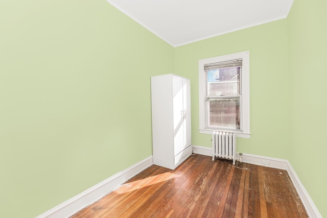 unfurnished room featuring crown molding, radiator heating unit, and dark wood-type flooring