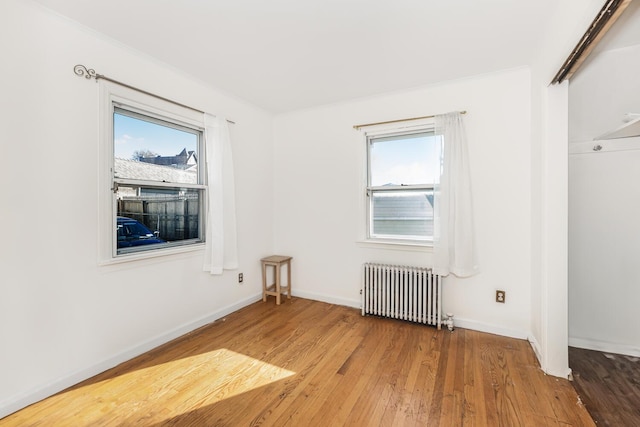 empty room featuring radiator, a healthy amount of sunlight, and wood-type flooring