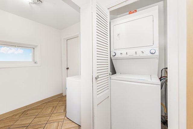 laundry area featuring light tile patterned flooring and stacked washing maching and dryer