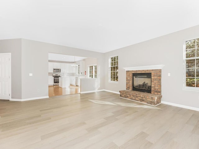 unfurnished living room featuring light wood-type flooring and a brick fireplace