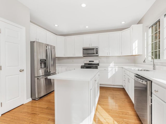 kitchen featuring appliances with stainless steel finishes, a center island, light hardwood / wood-style floors, and sink