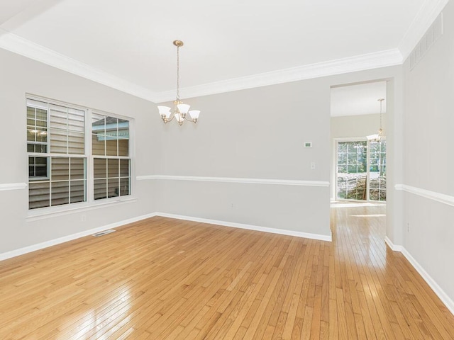 empty room featuring light hardwood / wood-style floors, crown molding, and a notable chandelier