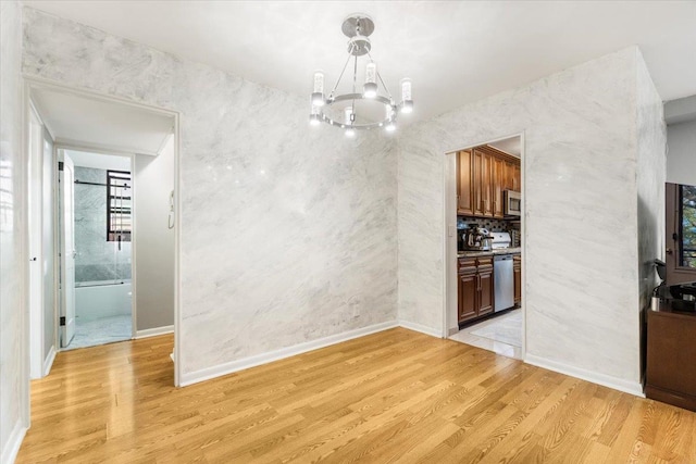 unfurnished dining area with a notable chandelier and light hardwood / wood-style flooring