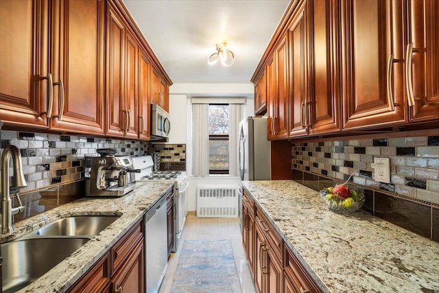 kitchen with sink, tasteful backsplash, light stone counters, radiator heating unit, and stainless steel appliances