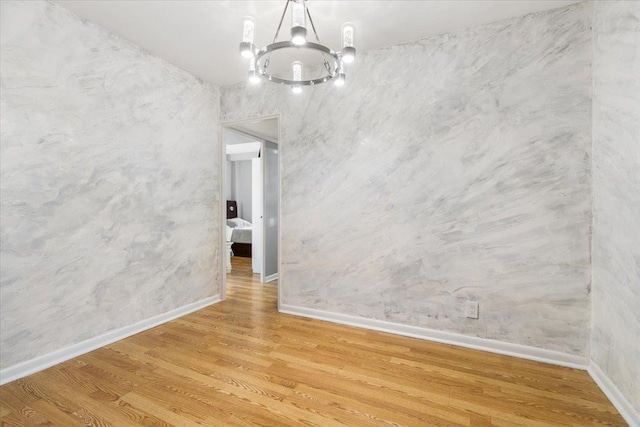 empty room with hardwood / wood-style floors and a notable chandelier