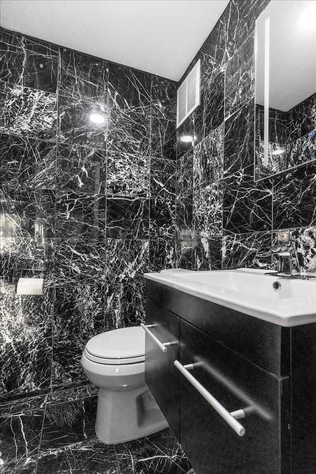 bathroom featuring vanity, toilet, and tile walls