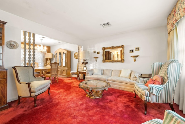 carpeted living room featuring decorative columns and an inviting chandelier