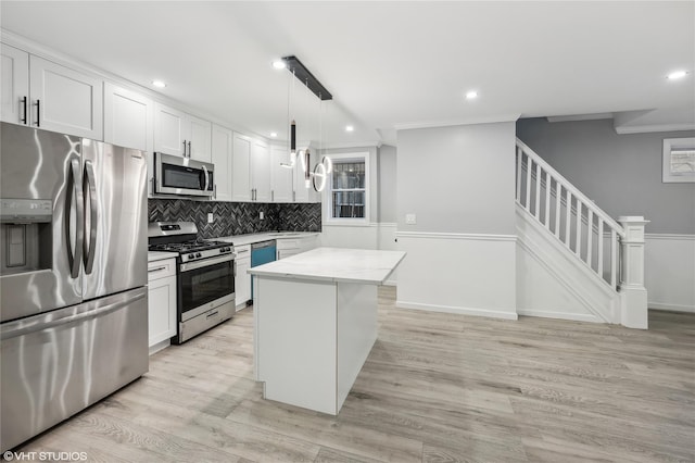 kitchen with a center island, white cabinets, light hardwood / wood-style flooring, appliances with stainless steel finishes, and decorative light fixtures