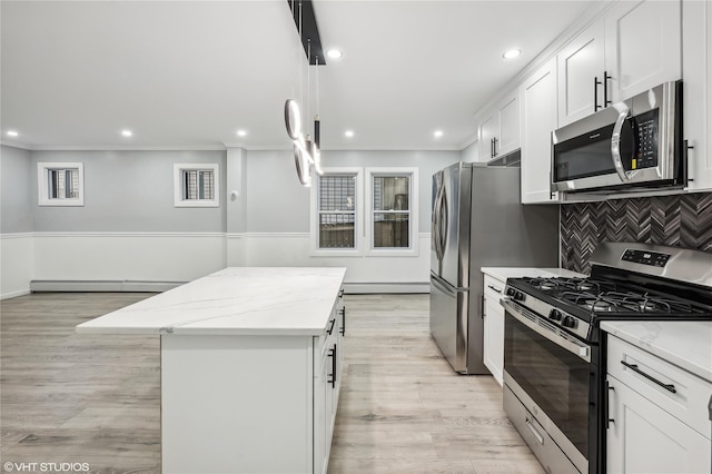 kitchen with white cabinetry, light stone counters, light hardwood / wood-style floors, a kitchen island, and appliances with stainless steel finishes