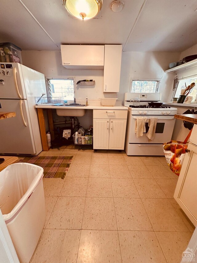 kitchen featuring white cabinetry, a wealth of natural light, sink, and white appliances