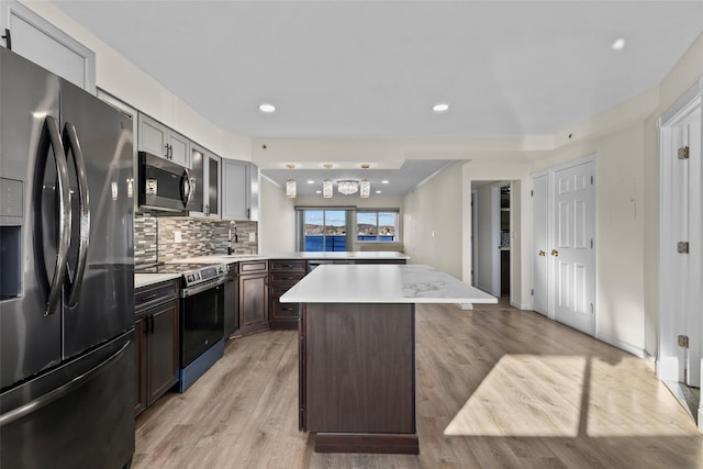 kitchen with a center island, sink, dark brown cabinets, light hardwood / wood-style floors, and stainless steel appliances