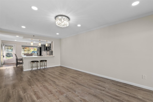 unfurnished living room featuring hardwood / wood-style floors, a notable chandelier, and ornamental molding