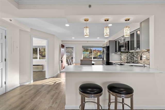 kitchen featuring plenty of natural light, kitchen peninsula, appliances with stainless steel finishes, and light hardwood / wood-style flooring