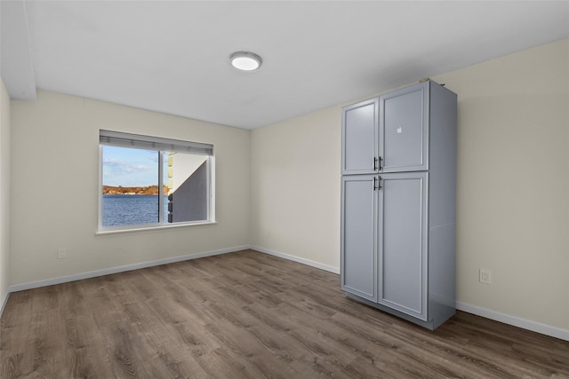 unfurnished bedroom featuring light hardwood / wood-style flooring and a water view