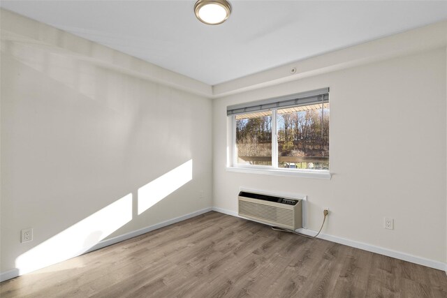 unfurnished room featuring wood-type flooring and an AC wall unit