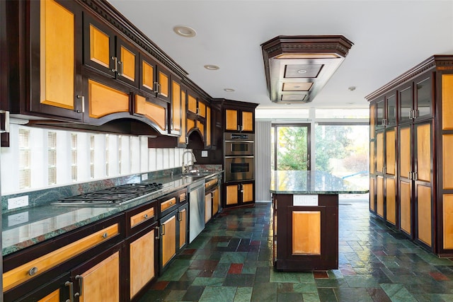 kitchen with stainless steel appliances, a kitchen island, dark stone counters, and sink