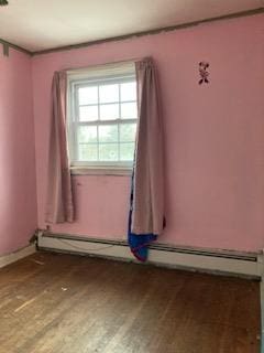 unfurnished room with hardwood / wood-style flooring and a baseboard heating unit