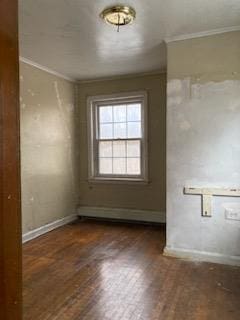 empty room featuring ornamental molding and dark wood-type flooring