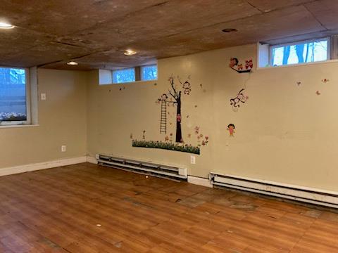 basement featuring wood-type flooring and baseboard heating