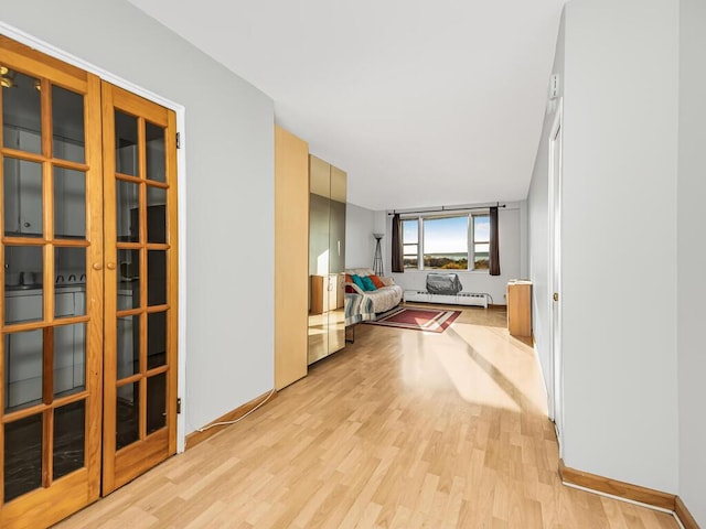 corridor with light wood-type flooring and baseboard heating