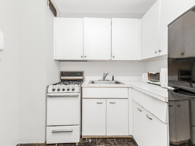 kitchen with white range oven, white cabinetry, sink, and black fridge