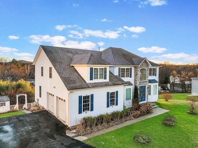 view of front of property featuring a garage, asphalt driveway, and a front lawn