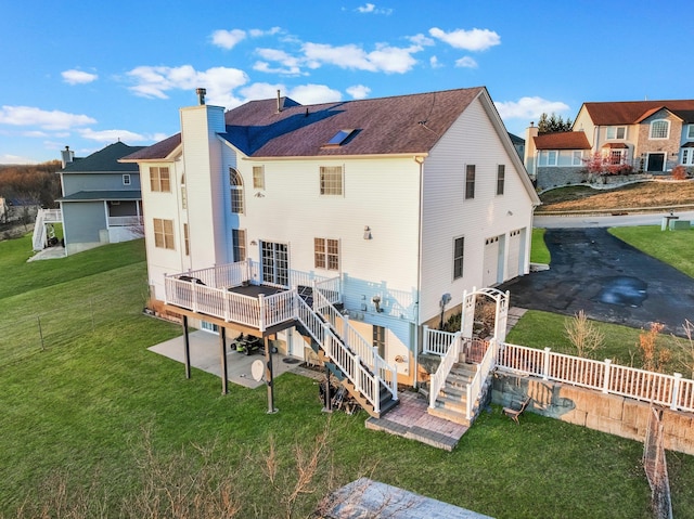 rear view of property featuring a chimney, a deck, stairs, an attached garage, and driveway