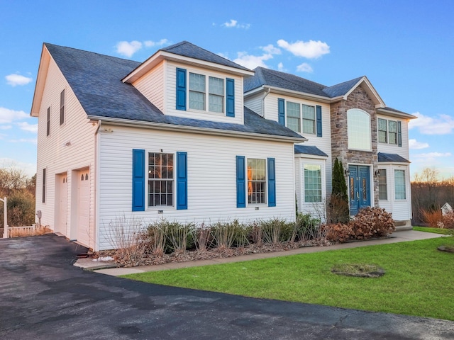 traditional-style home featuring a garage, driveway, and a front lawn