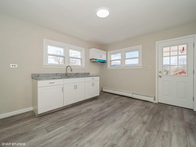 kitchen featuring a baseboard radiator, white cabinetry, a wealth of natural light, and light hardwood / wood-style flooring