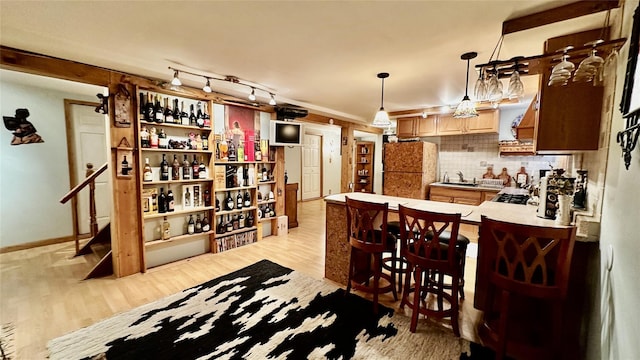 kitchen with decorative backsplash, kitchen peninsula, light wood-type flooring, hanging light fixtures, and a breakfast bar area