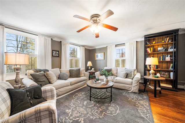 living room featuring ceiling fan, a healthy amount of sunlight, crown molding, and dark wood-type flooring